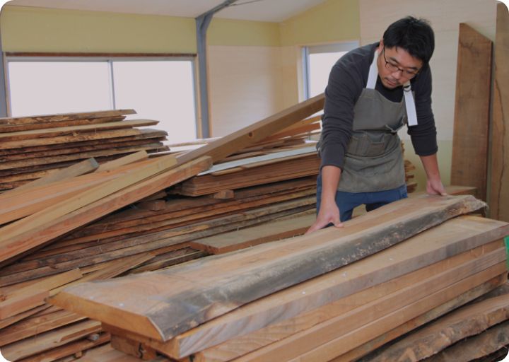 たくさんの無垢木材を置いている倉庫で木材を確認している様子